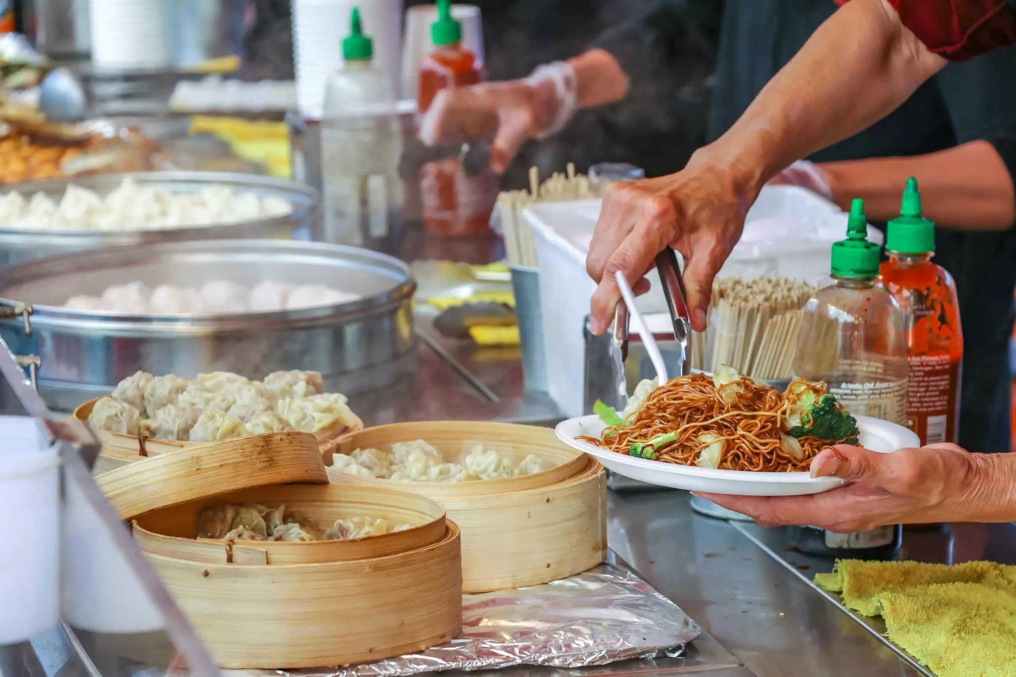 Piling food onto a plate. The night market is a popular destination on weekends in Richmond. Food is the highlight of the market.