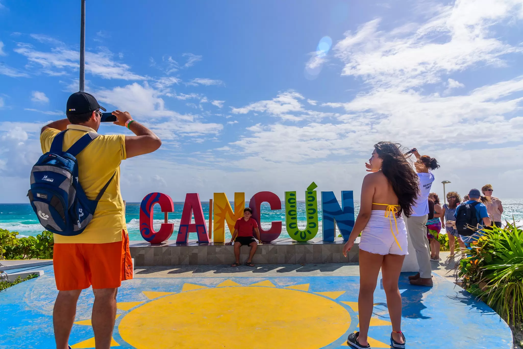 Tourists in front of the Cancun sign at Playa Delfines in Mexico