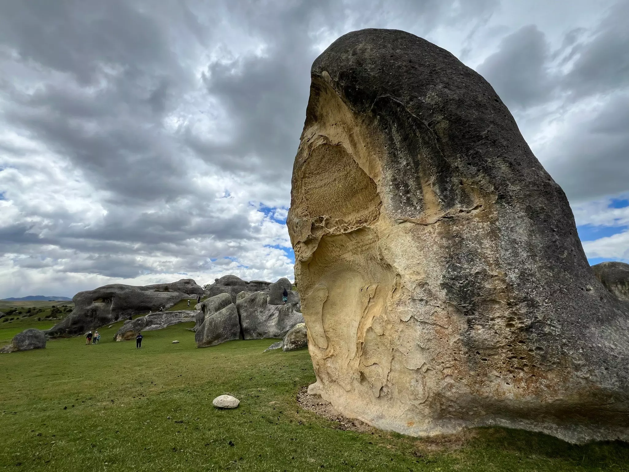 A series of massive freestanding boulders in a grassy landscape.