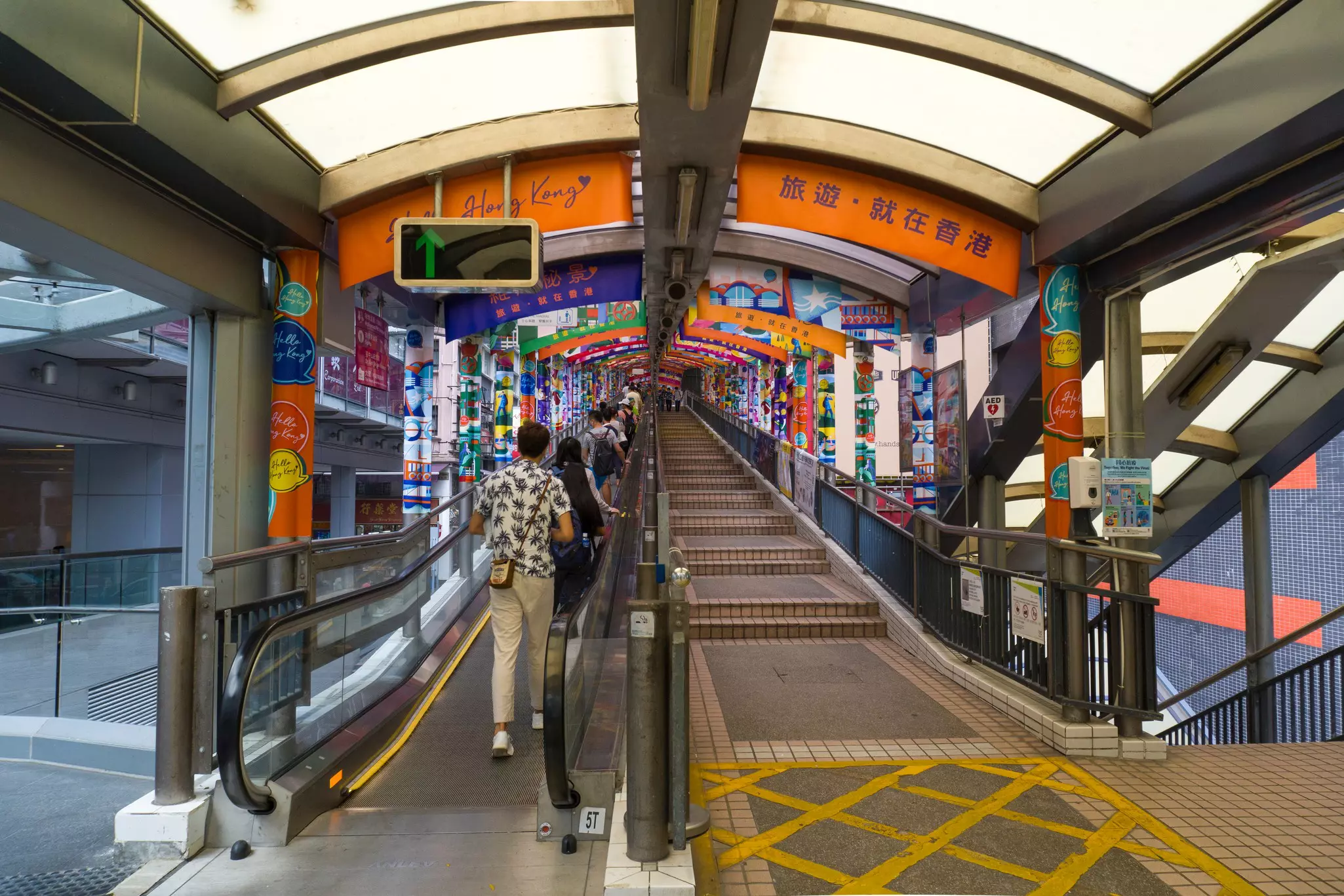 People traveling in a colorful tunnel on the Central-Mid-Levels Escalator