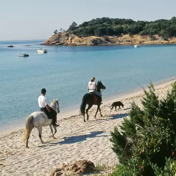 Horse riders on Palombaggia Beach near Porto Vecchio on the island of Corsica, France.