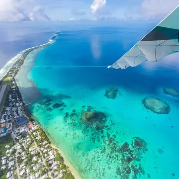 Tuvalu under the wing of an airplane. Aerial view of Funafuti atoll and the airstrip of International airport in Vaiaku. Fongafale motu. Island nation in Polynesia, South Pacific Ocean, Oceania.