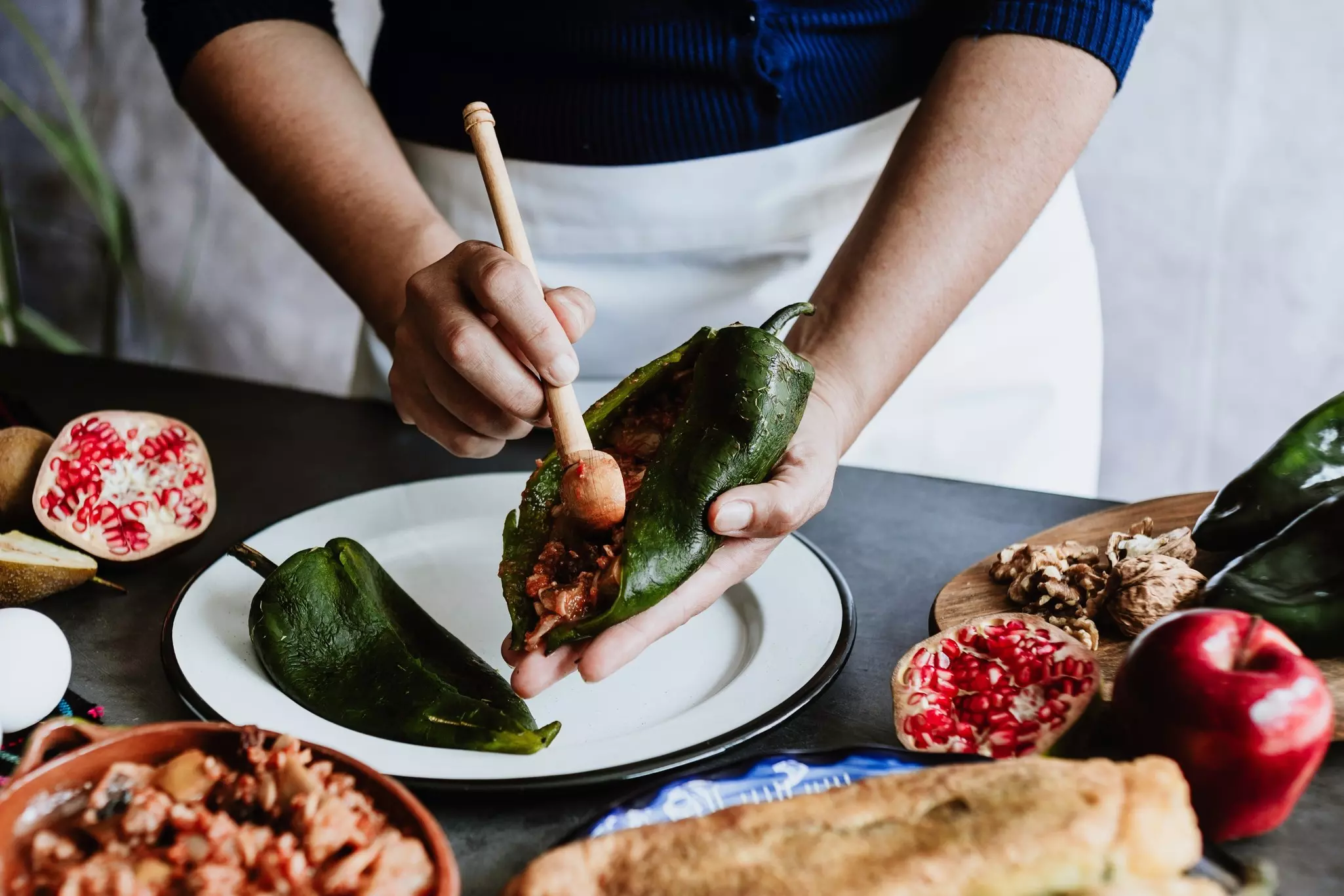 mexican woman preparing and cooking chiles en nogada recipe with Poblano chili and ingredients,