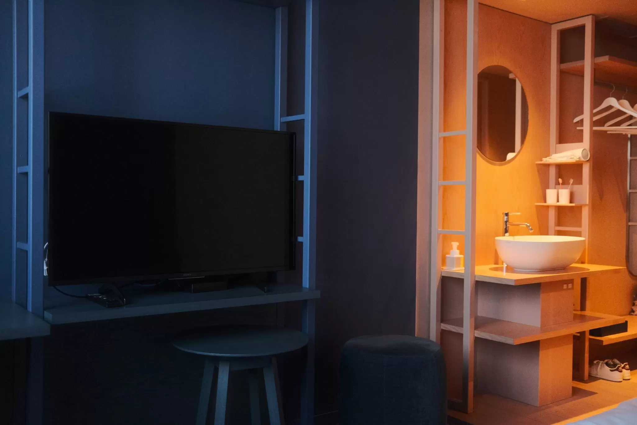 A hotel room in Tokyo with a large flat-screen television on the wall and a basin sink and mirror off to the side
