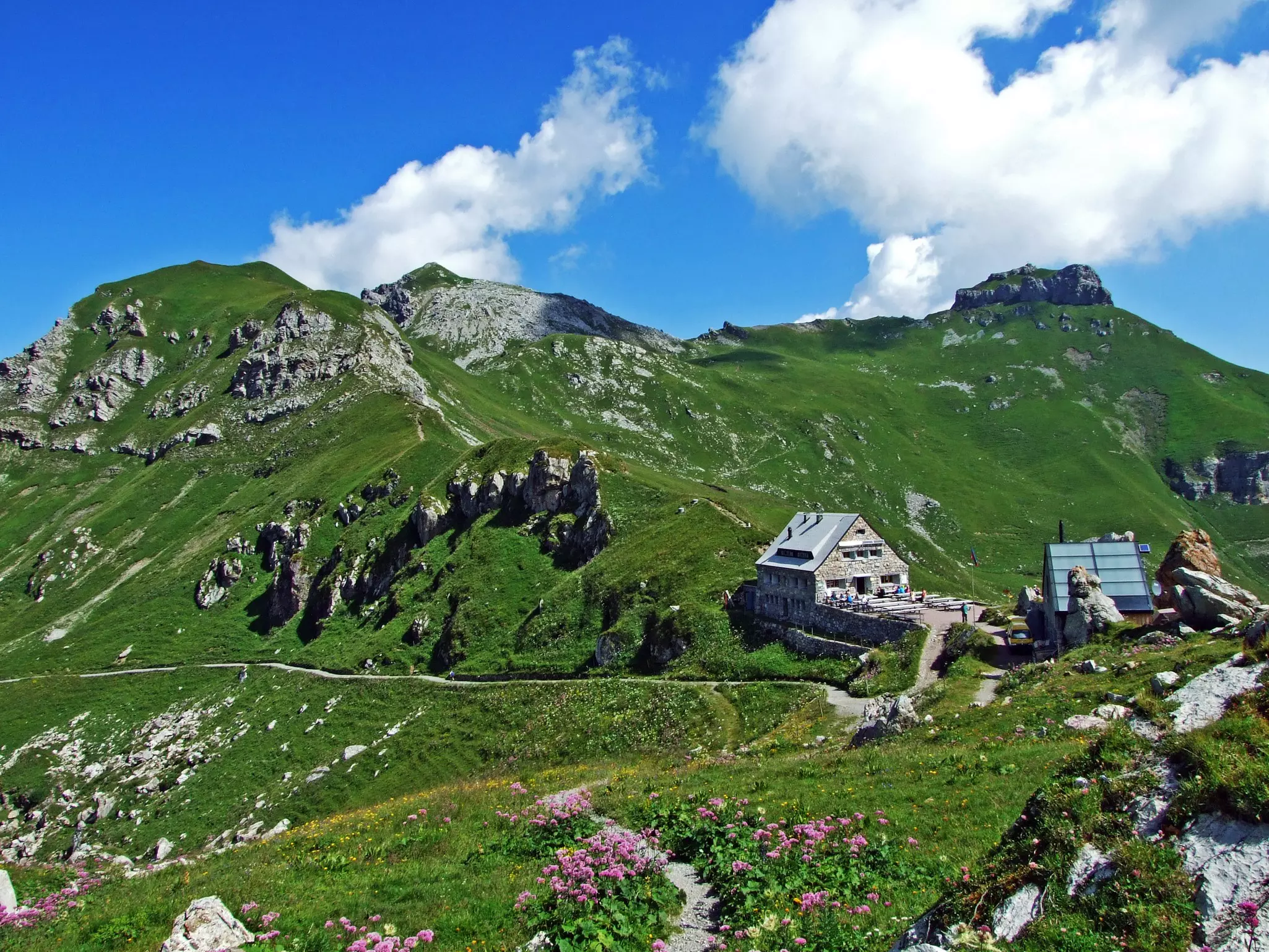 A mountain hut surrounded by peaks on a summer's day.
