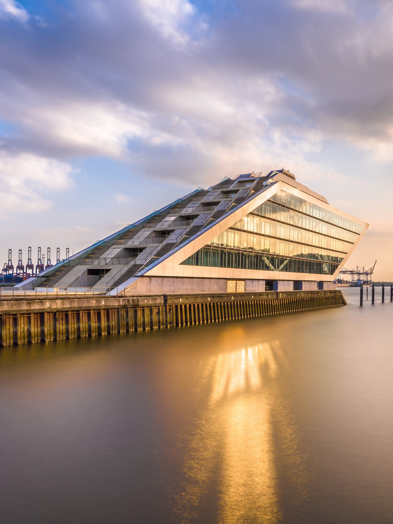 The Dockland is a striking office building with a staircase accessible for visitors and a view over the harbor in Hamburg, Germany.