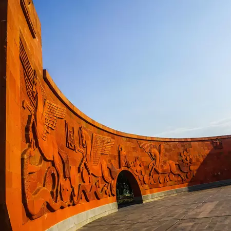 An orange curved wall with illustrations carved into it