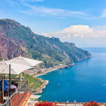 Open-air street cafe with umbrellas in Ravello village, overlooking the Tyrrhenian sea, Amalfi Coast, Italy. 