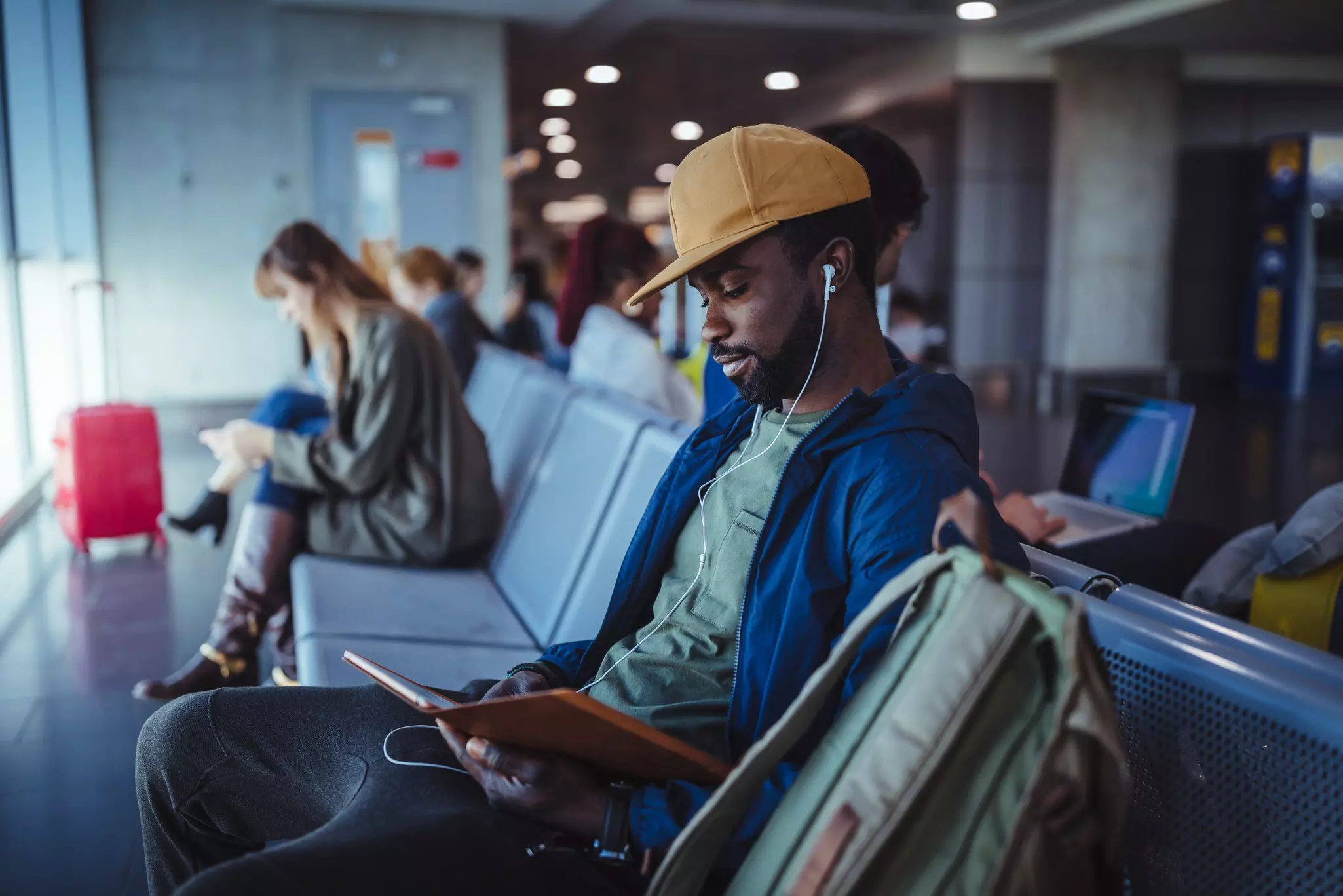 A man is using his phone and wearing headphones in an airport