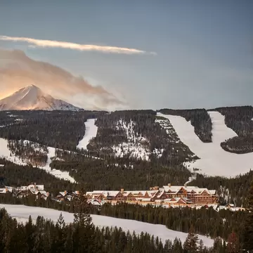 A tall mountain in the background. In the foreground a sprawled out ski resort with ski slopes surrounding it: Montage Big Sky resort in Montana