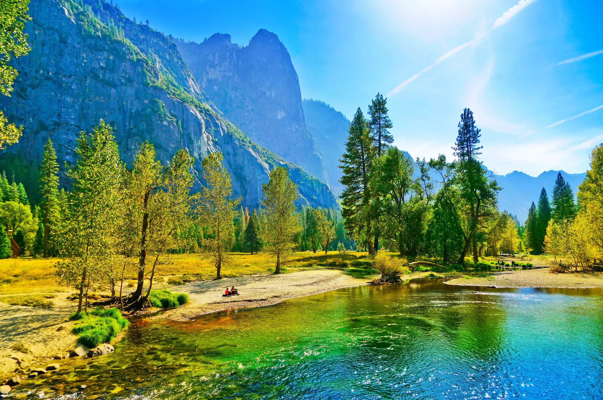 People sit on the banks of the Merced river in the Yosemite Valley during autumn.