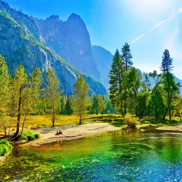 People sit on the banks of the Merced river in the Yosemite Valley during autumn.