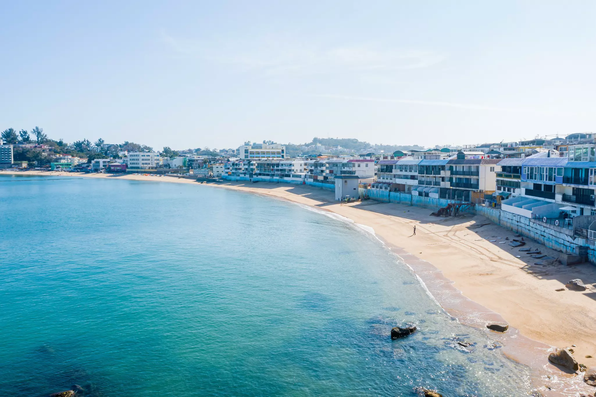A long gentle curve of sand backed by homes and buildings.