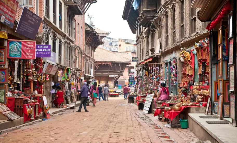 Brick lane in Bhaktapur, Nepal, lined with shops selling masks, thangkas and brass; signs read Genuine Wood Craft