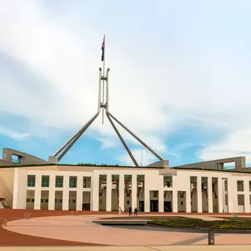 A low modern government building topped with a tall flagpole spire.