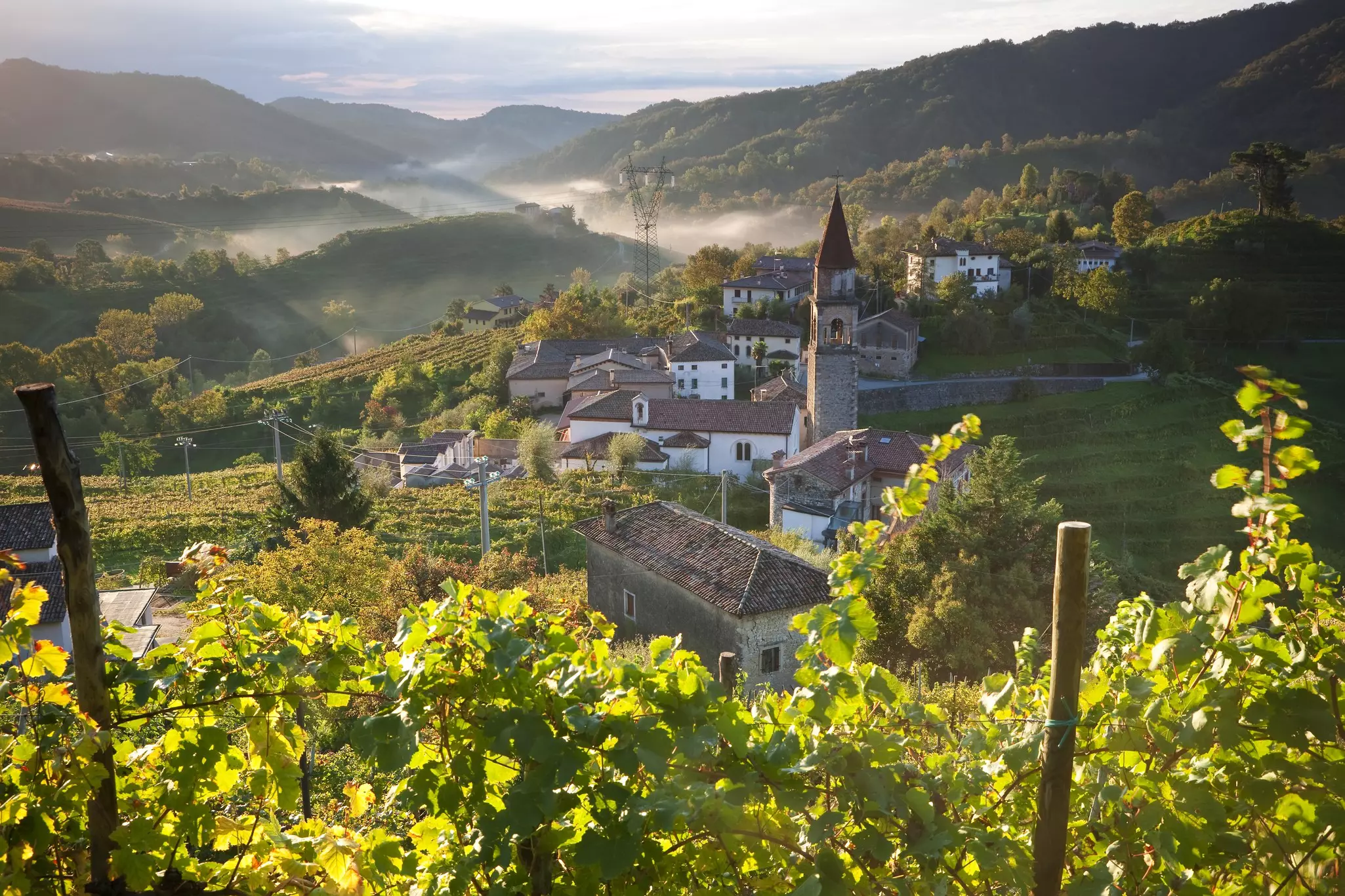 Prosecco vineyards rise above a stone village in the hills of Veneto, Italy.