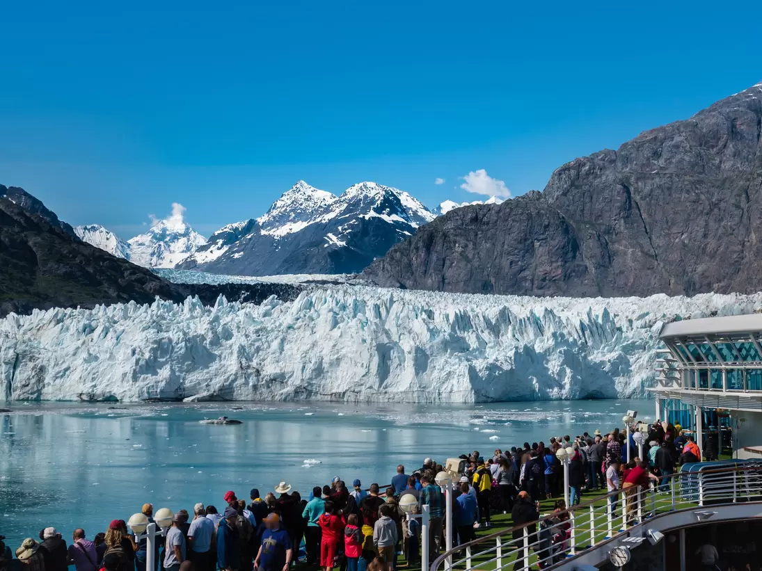 A group of tourists are enjoying the gorgeous view of the Margerie Glacier in the Glacier Bay of Alaska on a sunny day.