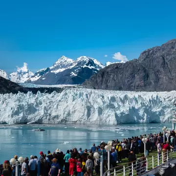A group of tourists are enjoying the gorgeous view of the Margerie Glacier in the Glacier Bay of Alaska on a sunny day.