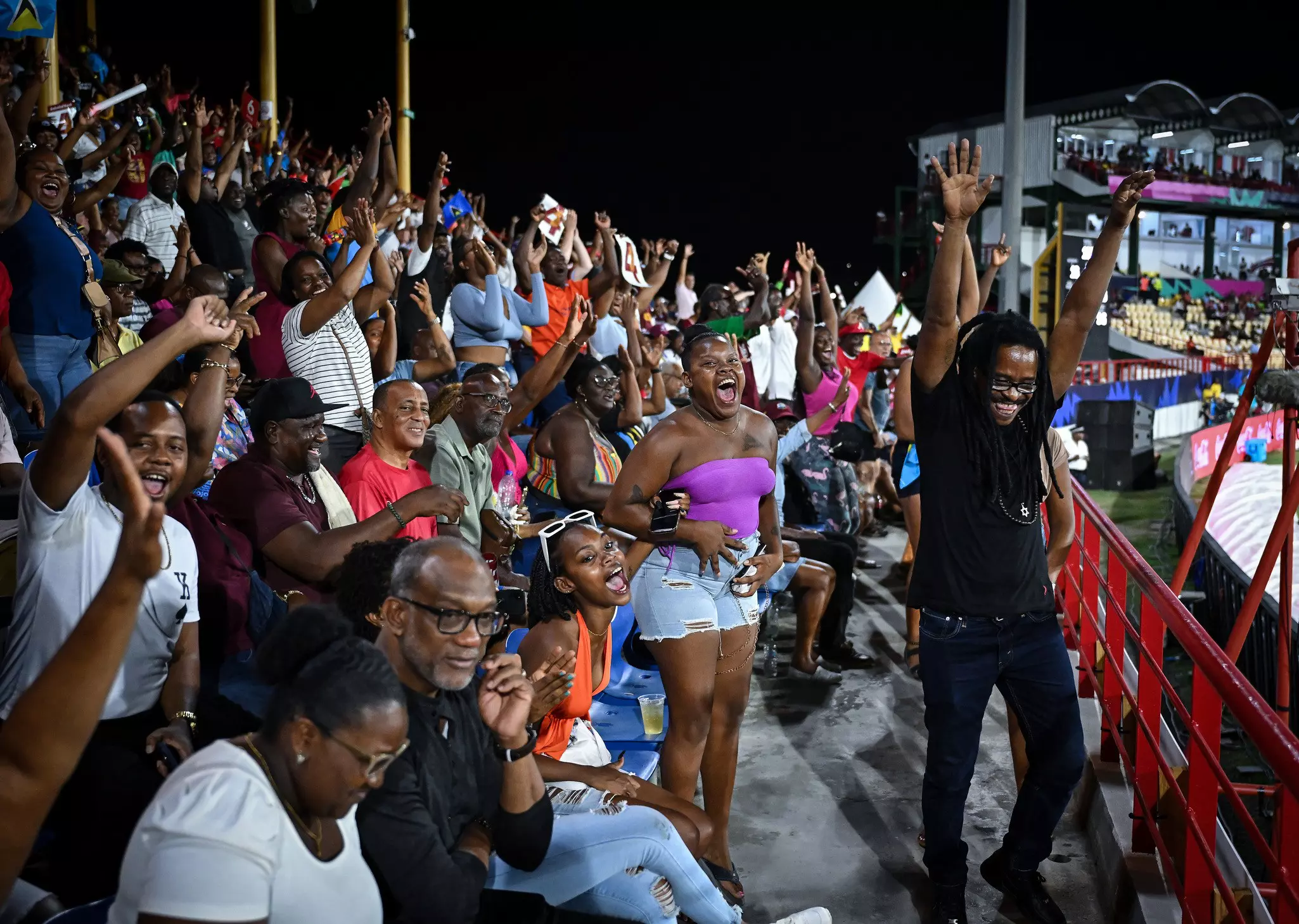 People in the bleachers of a crowded stadium cheer.