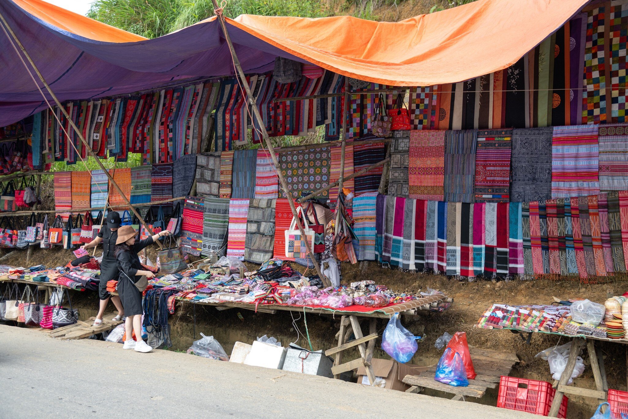 Colorful traditional clothing and items for sale at Can Cau Market in Vietnam.