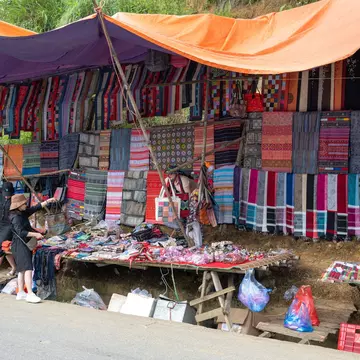 Colorful traditional clothing and items for sale at Can Cau Market in Vietnam.