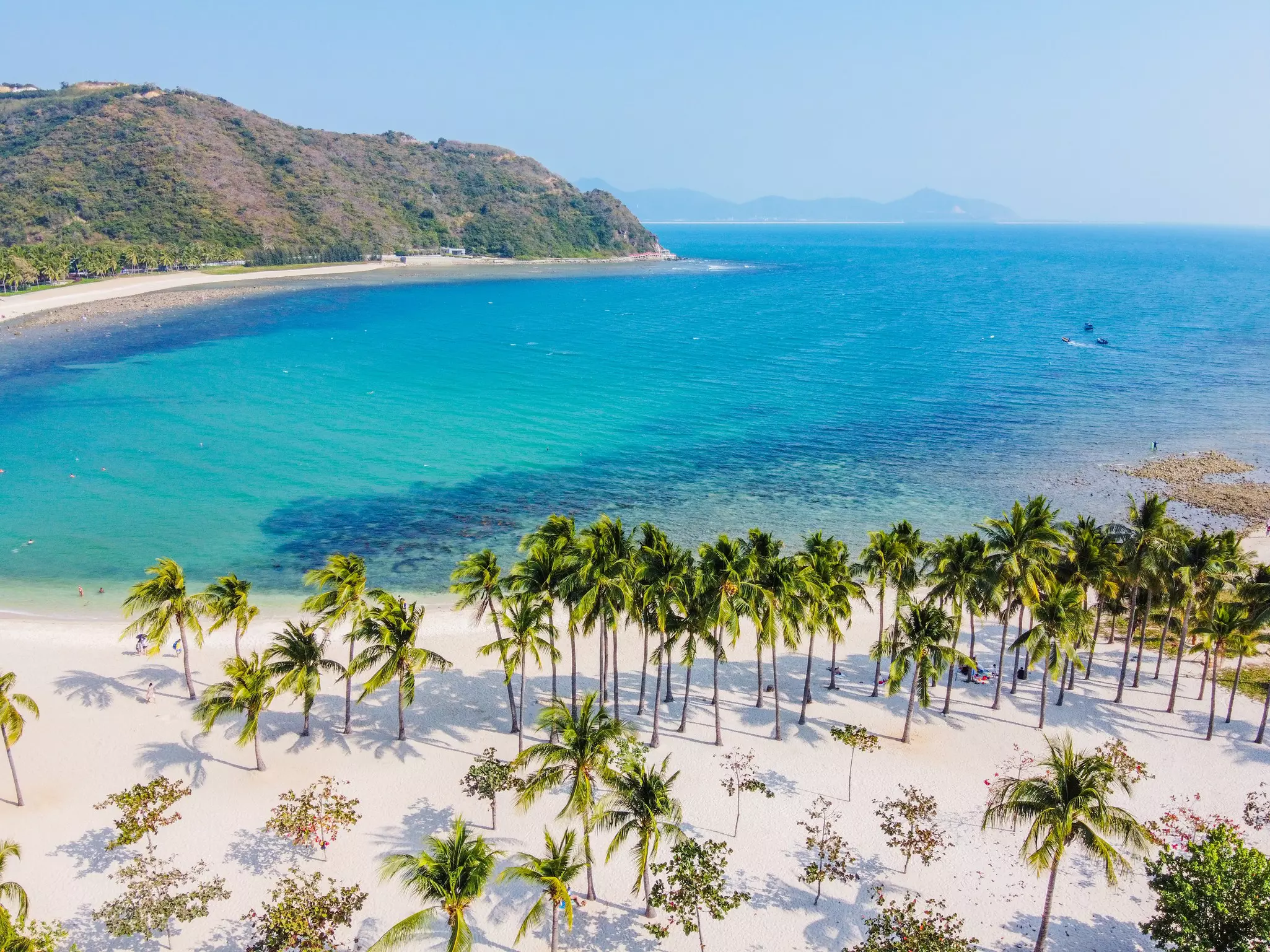 View over palms, white sand and turquoise water at Xiaodonghai beach, Sanya, Hainan, China.