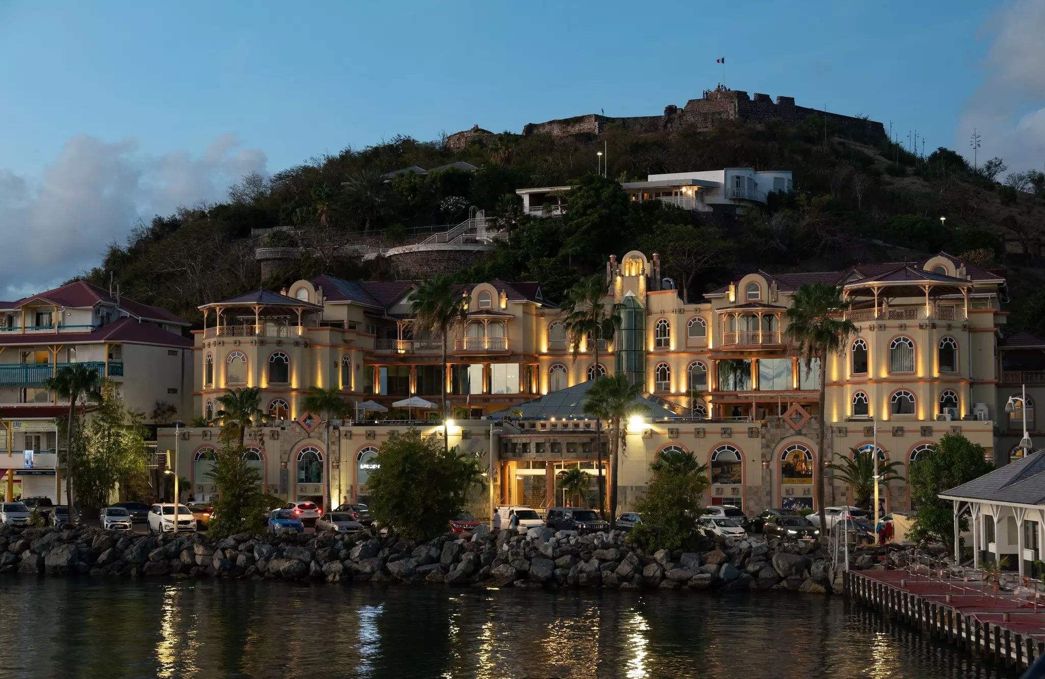 Buildings along the port of a village are illuminated at dusk.