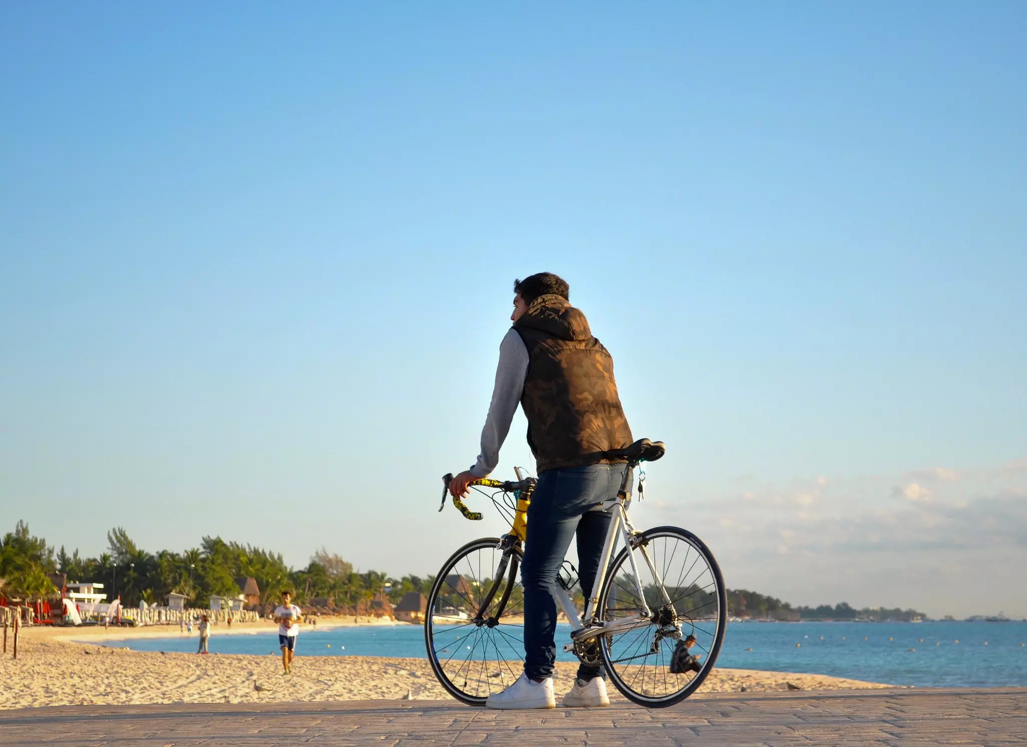 Young male standing on the beach with his bike on Playa del Carmen Mexico