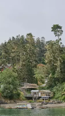Buildings built into the rocky hill surrounded by trees a dock juts out into the water