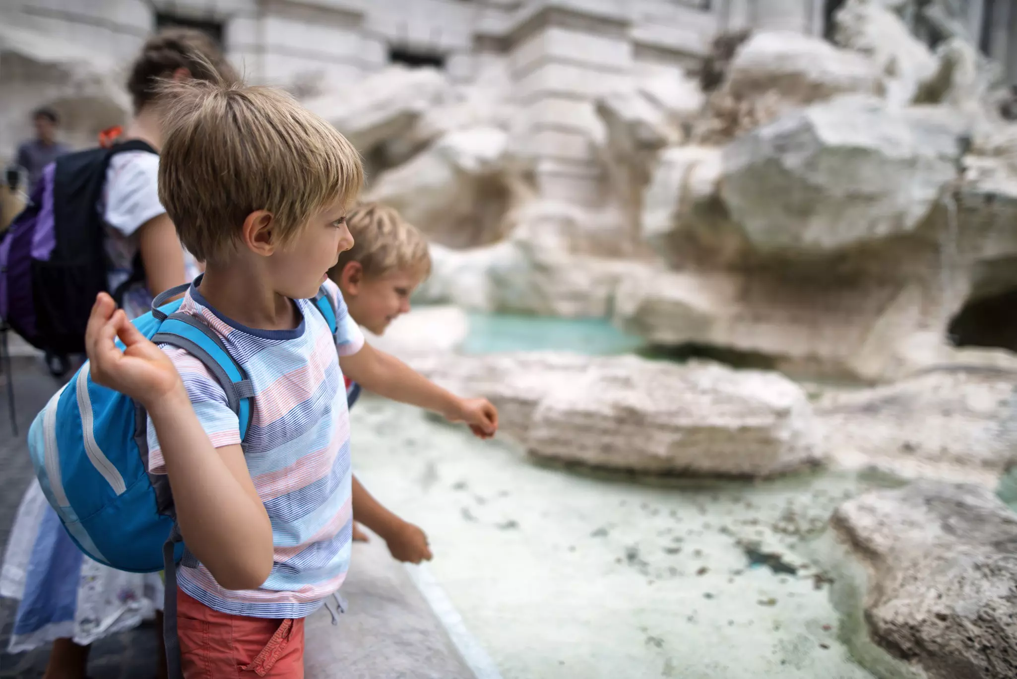 Close-up of kids throwing coins into Trevi Fountain in Rome ©Imgorthand/Getty Images