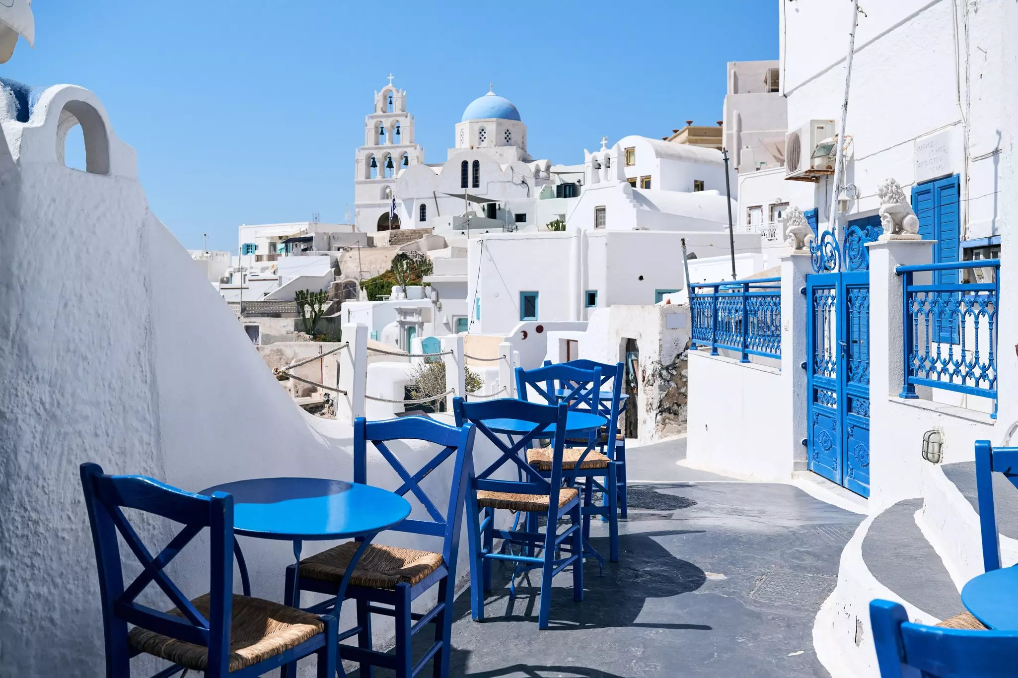 Typical street with blue tables and chairs among white houses on the Greek island of Santorini, Pyrgos