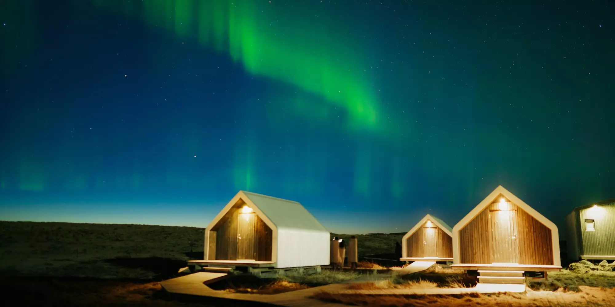 Wonderful Northern lights or Aurora borealis glowing over illuminated huts in autumn on arctic circle at Iceland