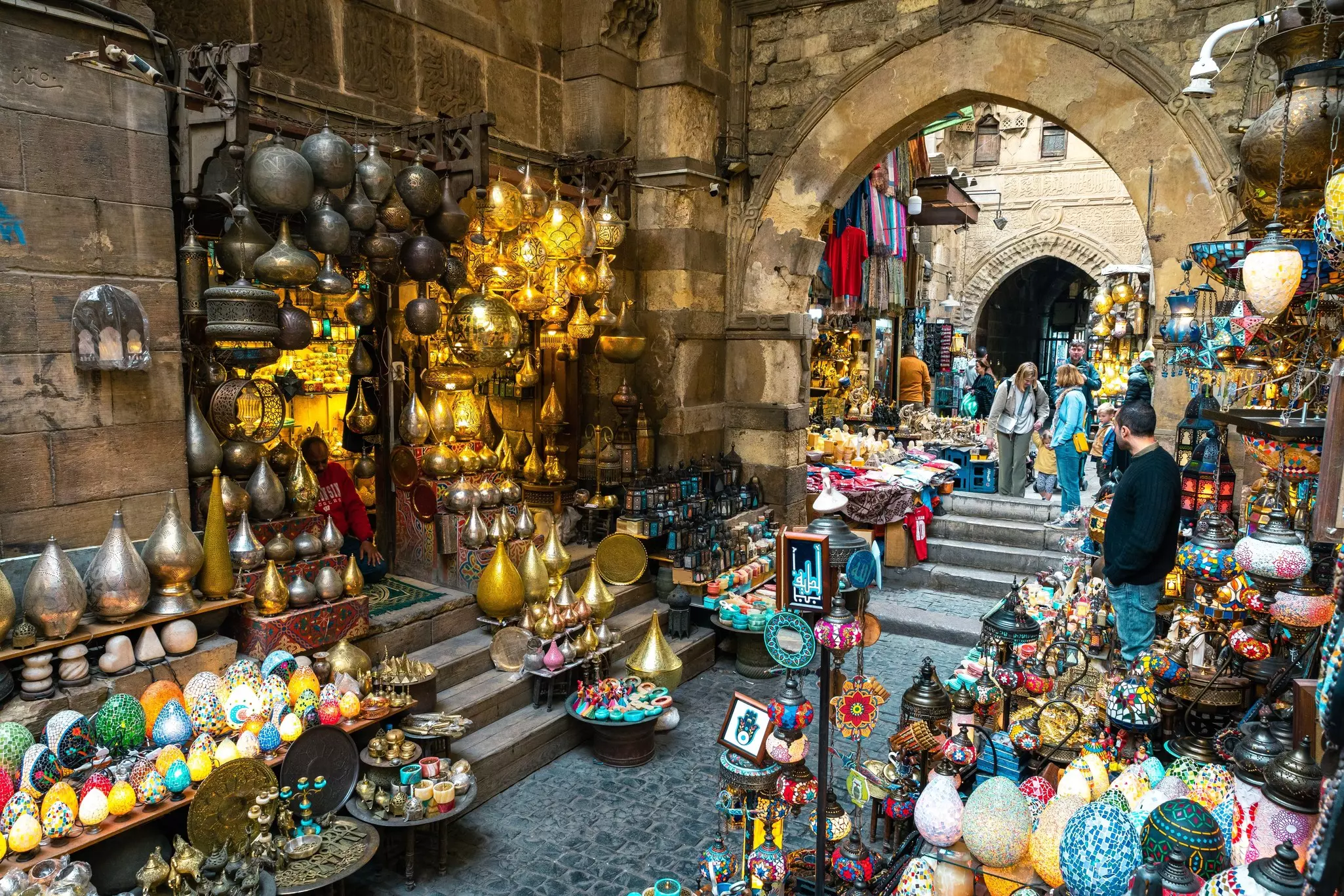 An alleyway in a bazaar lined with lanterns and colorful lamps for sale.