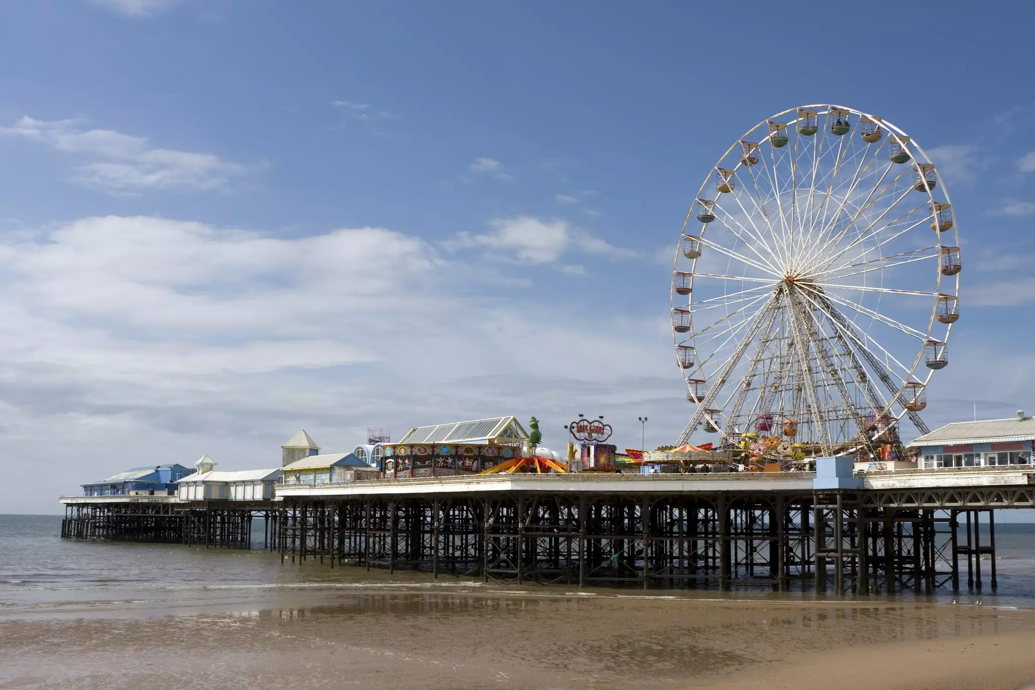 The Ferris wheel on Central Pier with fairground rides in the seaside town of Blackpool, Lancashire, UK.