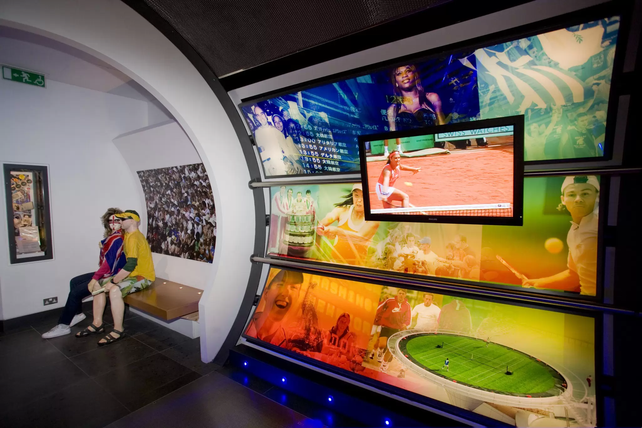 A view of the inside of the Wimbledon Lawn Tennis Museum, showing exhibitions and photographs lit up on the walls.