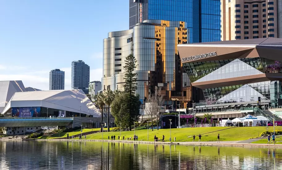 Adelaide Convention Centre and Festival Centre on the River Torrens, Adelaide, with joggers on the lawn and towers behind