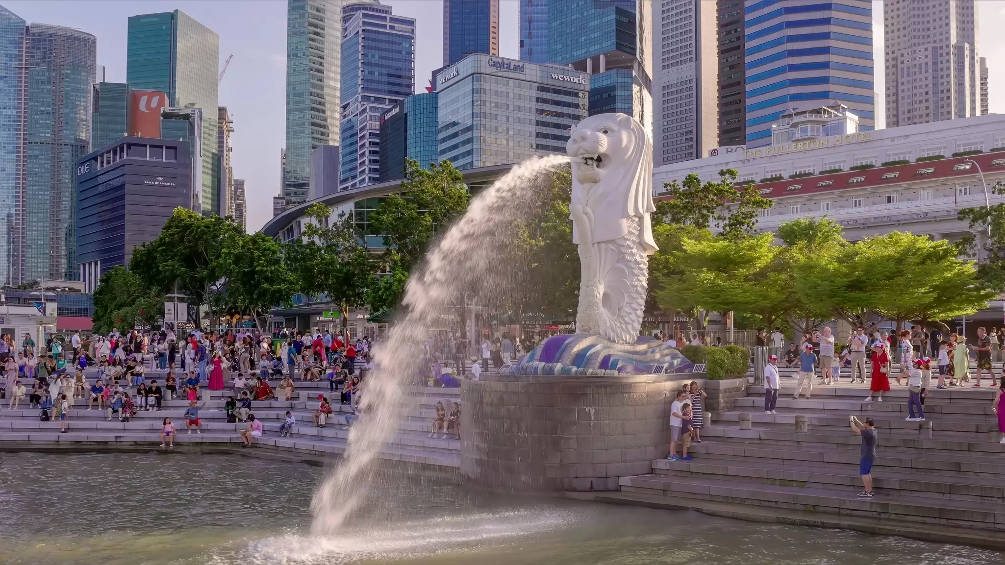 A statue shaped like a mythical beast shoots water into the harbor of a city.