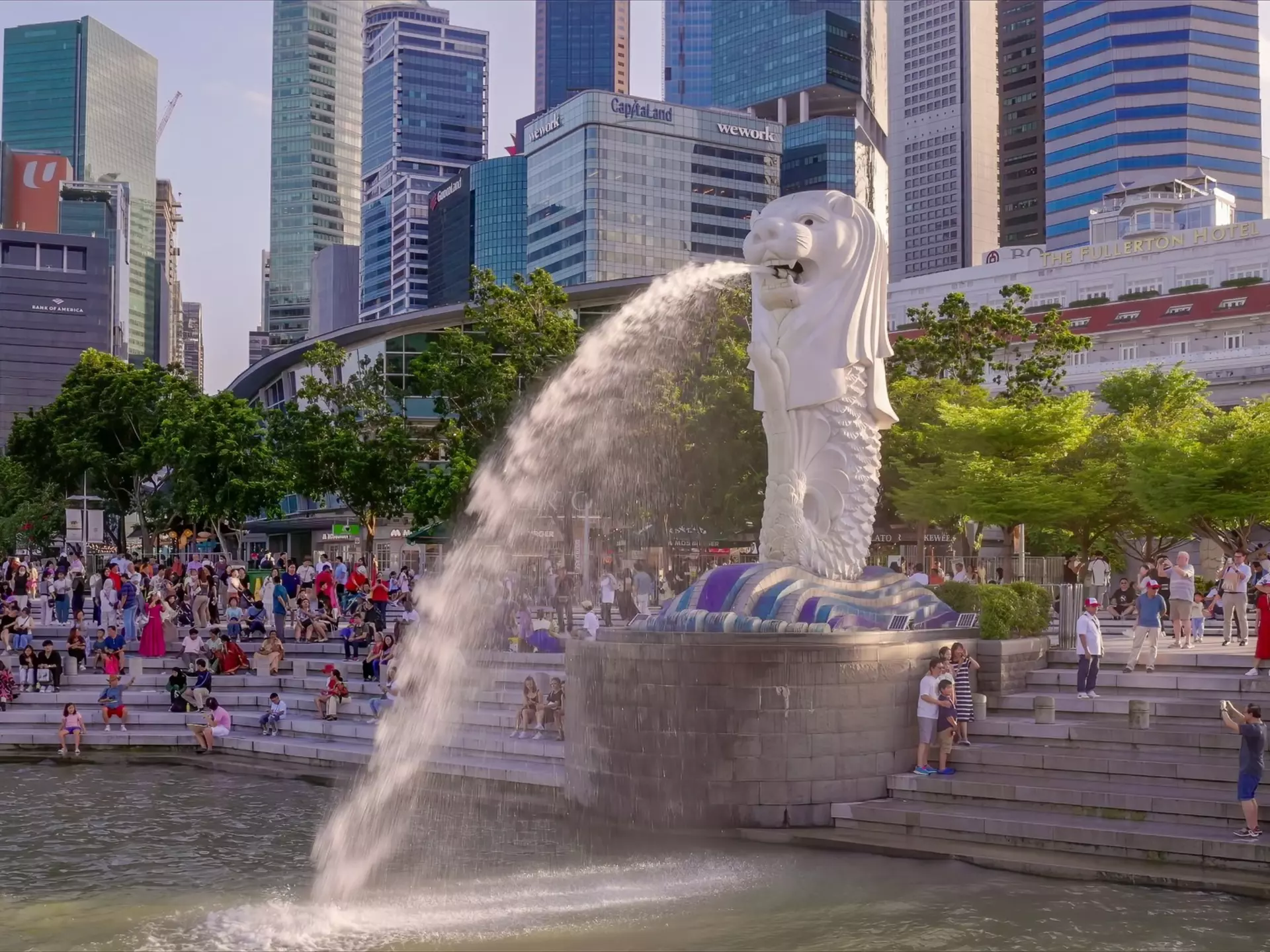 A statue shaped like a mythical beast shoots water into the harbor of a city.