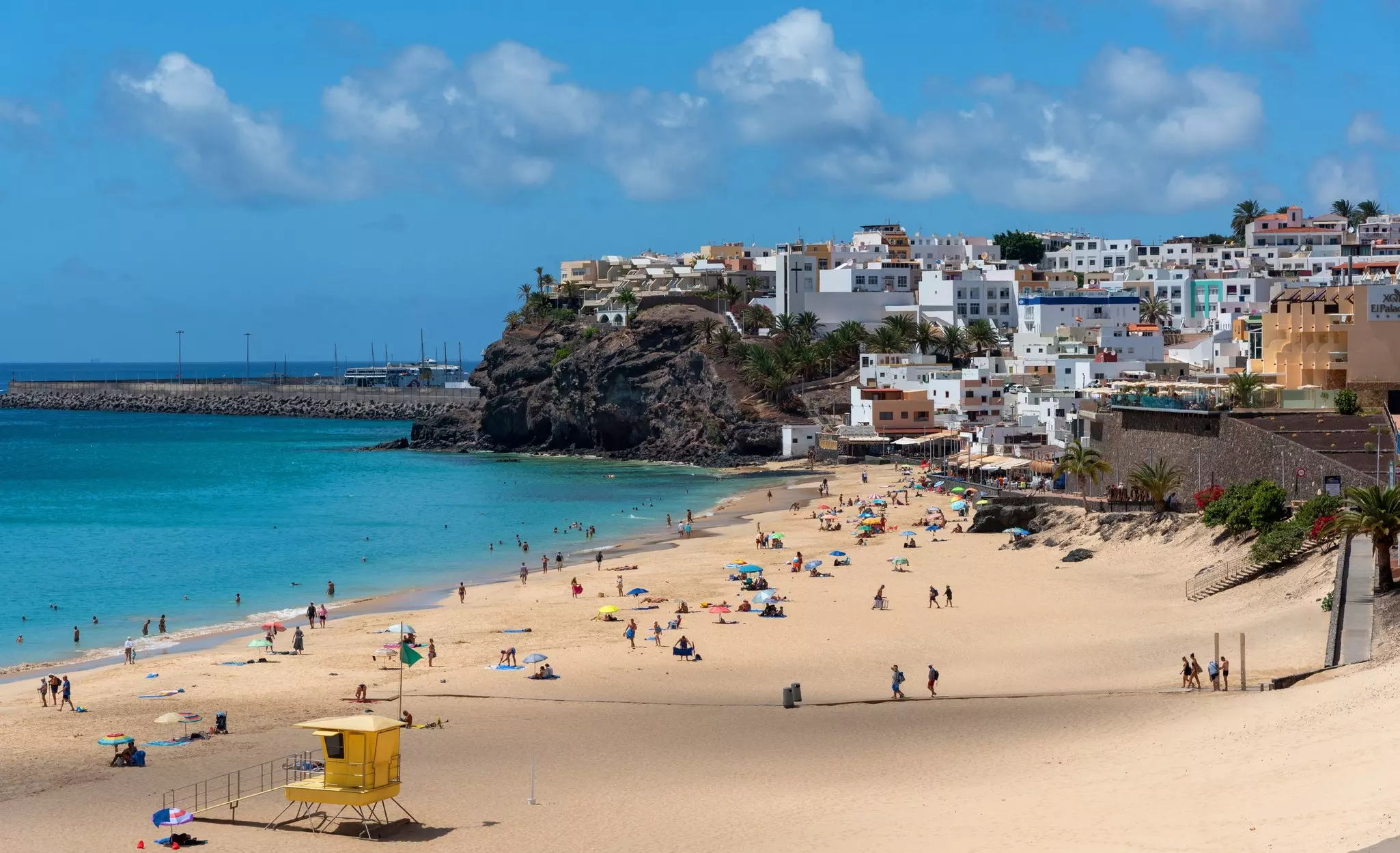 Panoramic view of the Morro Jable beach with white sand and turquoise sea full of people enjoying the sun with the village in the background the traditional architecture Fuerteventura Canary Islands