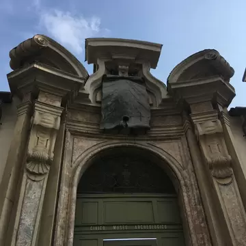 Stone and marble doorway with scrolled pediments and a bronze inscription, CIVICO MUSEO ARCHEOLOGICO on the green door