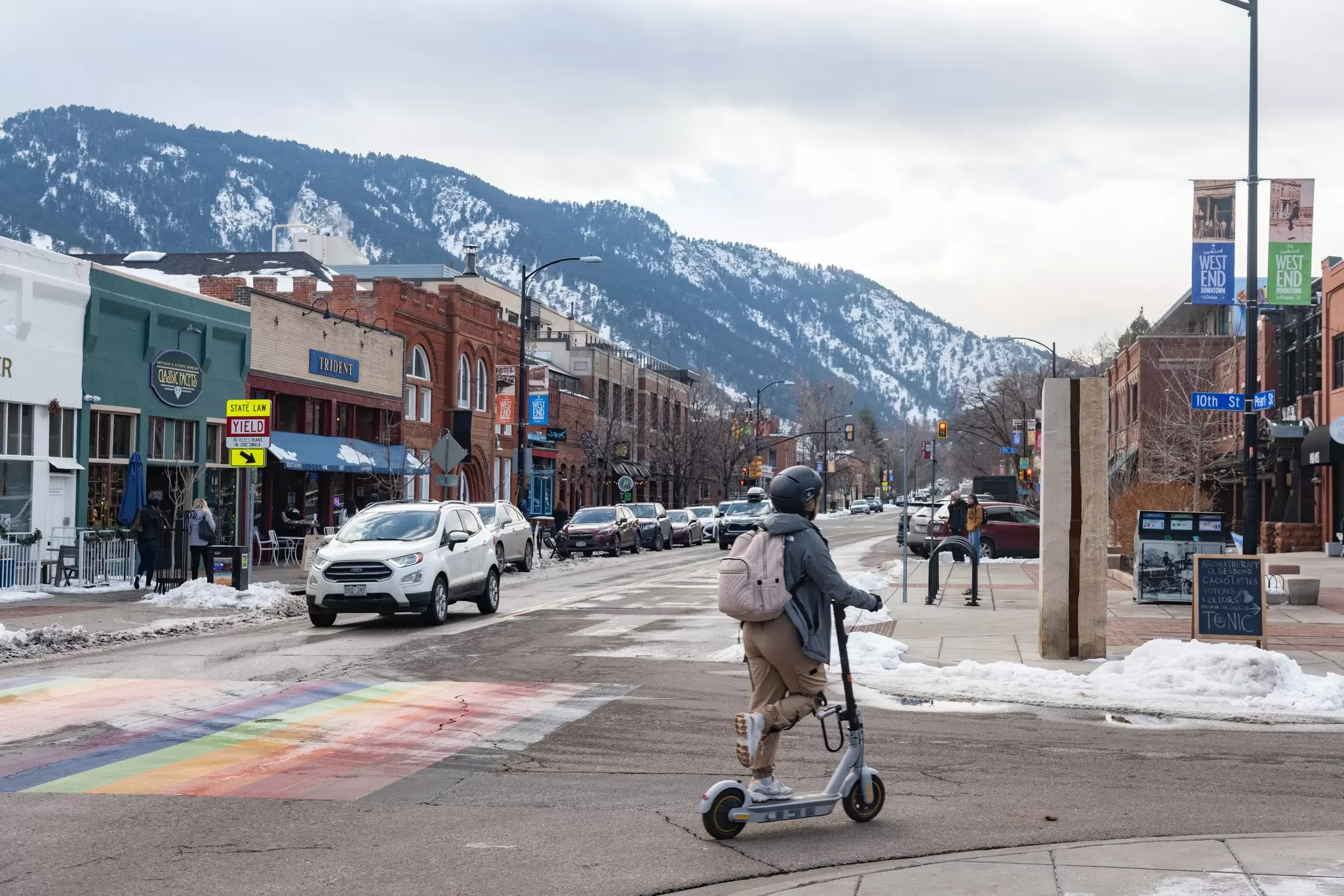 A person rides an e-scooter on a snowy day in a city street: transport in Boulder, Colorado
