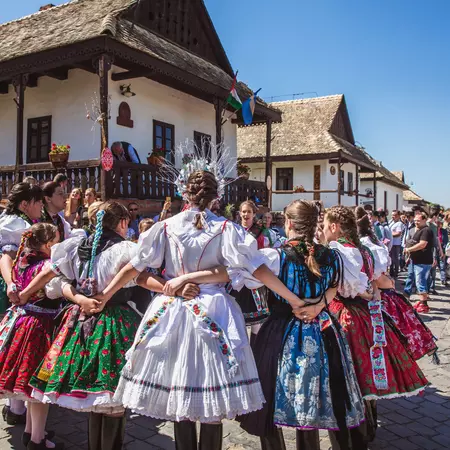 People in festival dress clasp arms in a circle