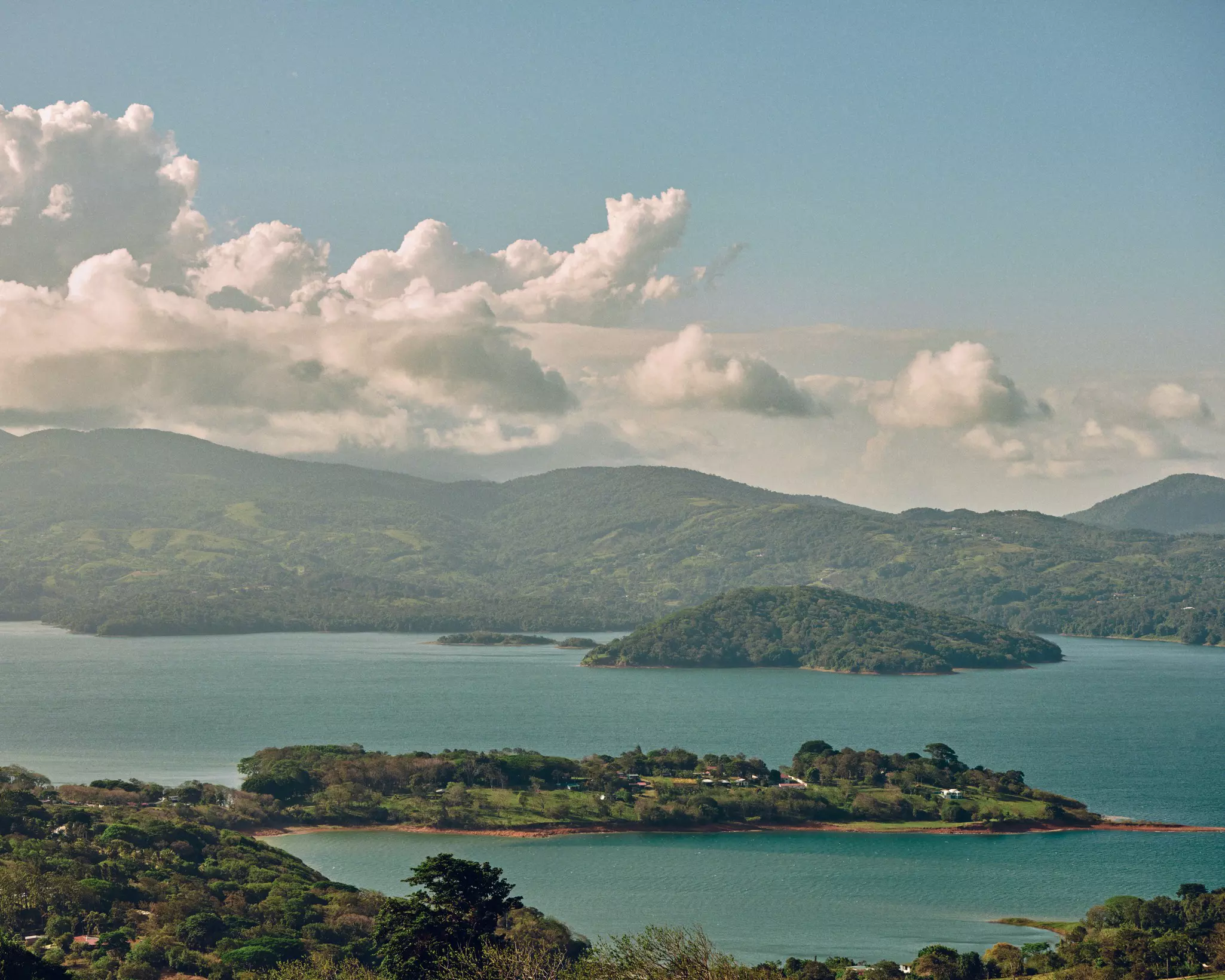 A blue lake surrounded by jungle landscape on a partly cloudy day