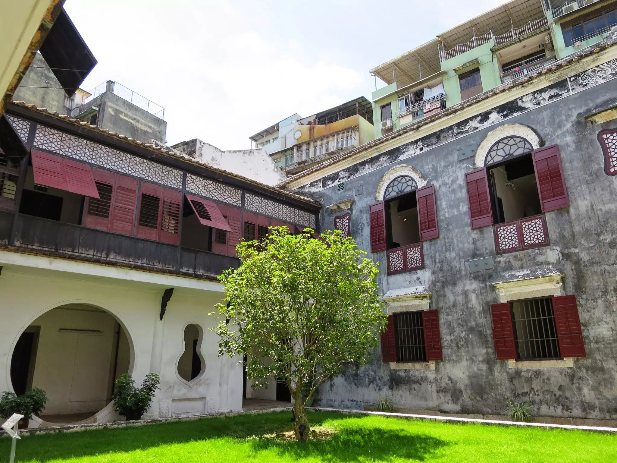 Part of Mandarin's House, which comprises 22 buildings, with a tree and grass in front and a pale sky