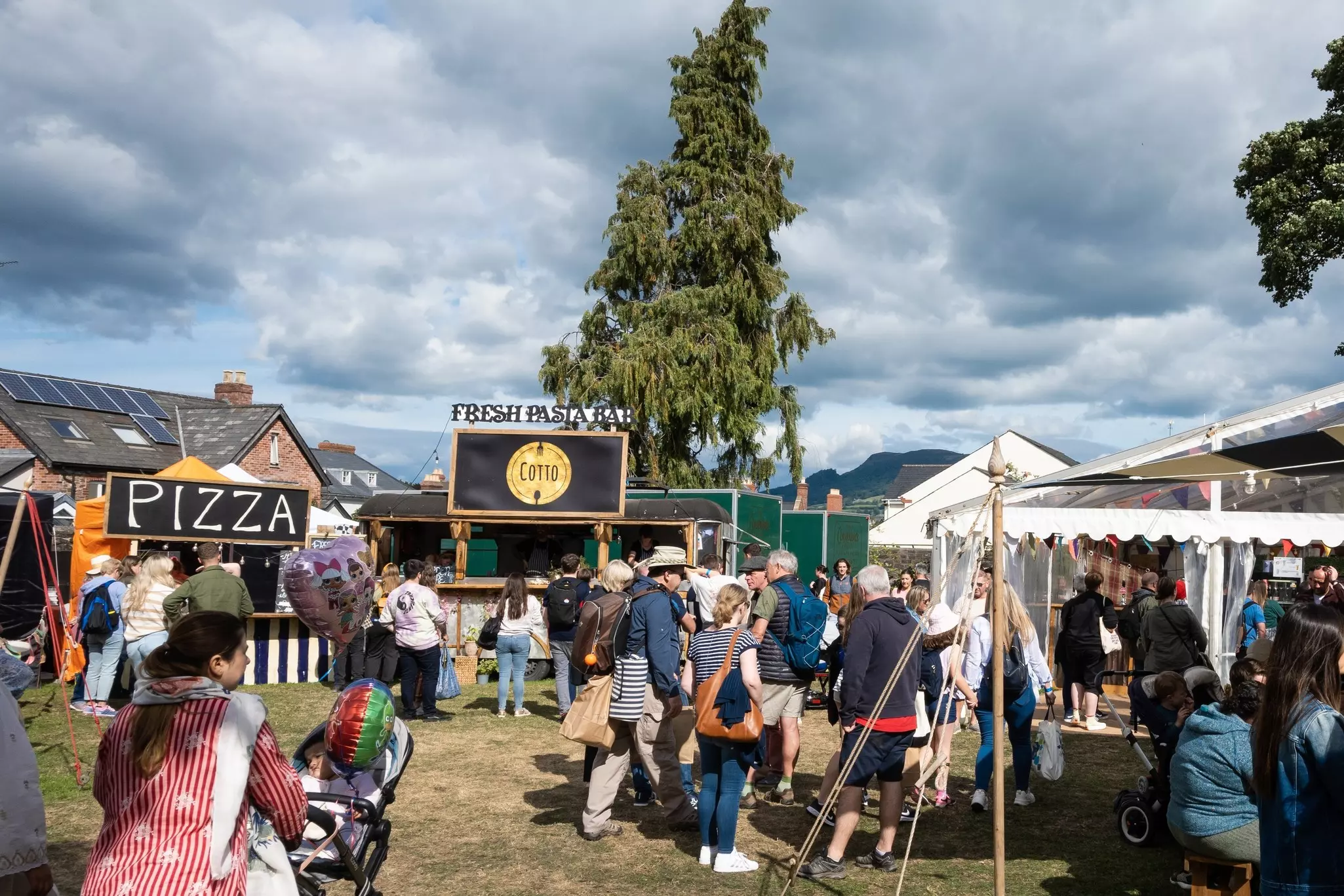 People gathered around food vendor tents and booths in a grassy area