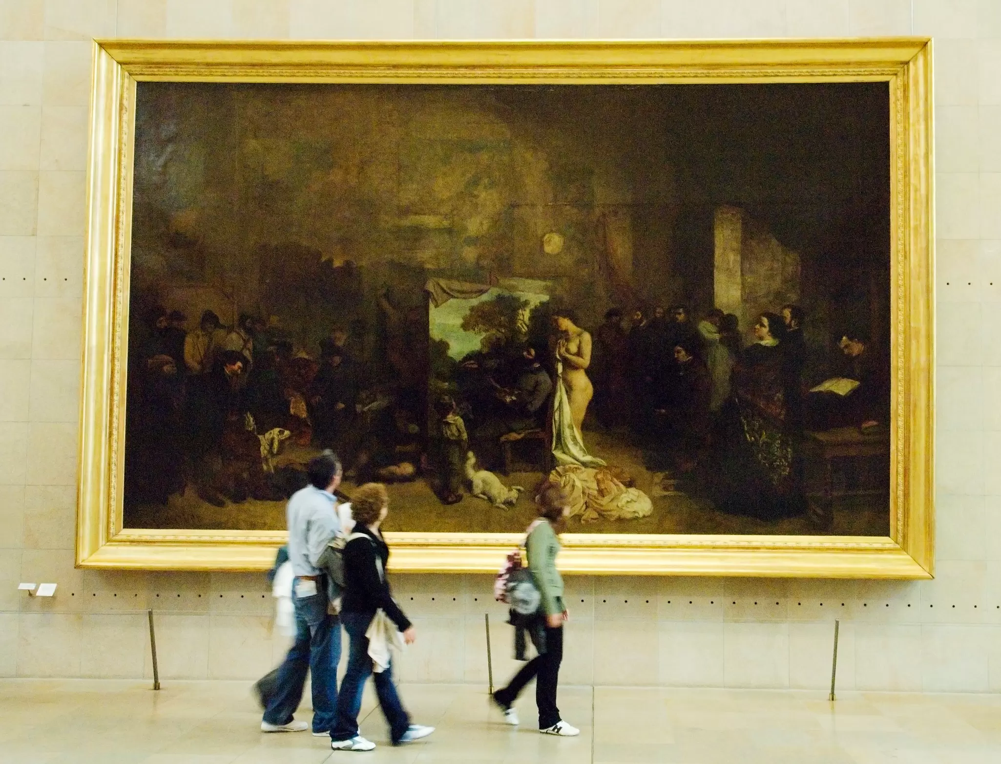Visitors walking past and admiring a large painting in the Musée d'Orsay.