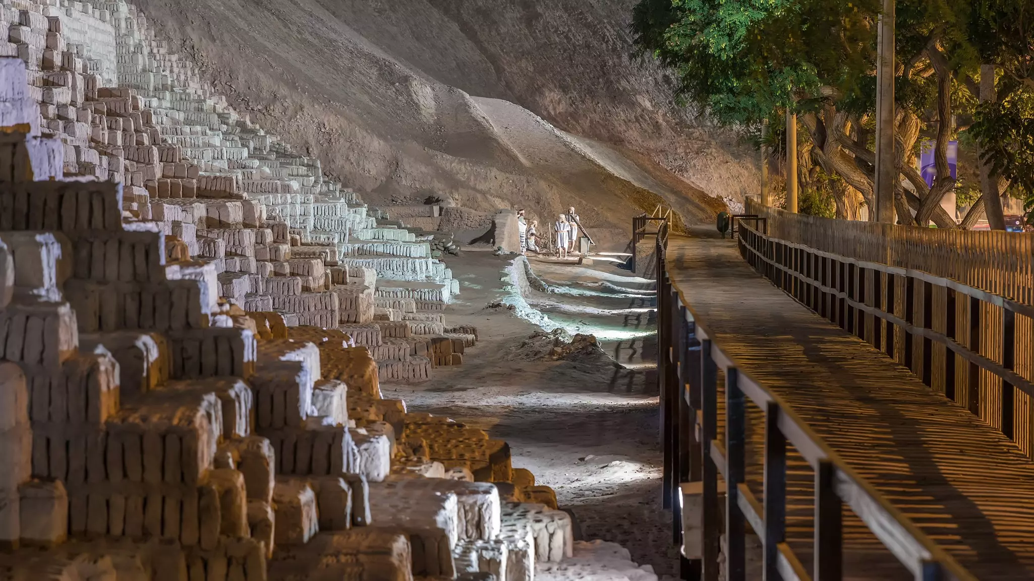 The stones of an ancient pyramid located in a city park are illuminated at night.