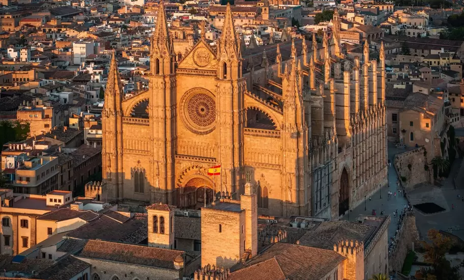 Palma de Mallorca's Gothic cathedral and the crenellated Almudaina Palace seen from above, city sprawling to distant hills