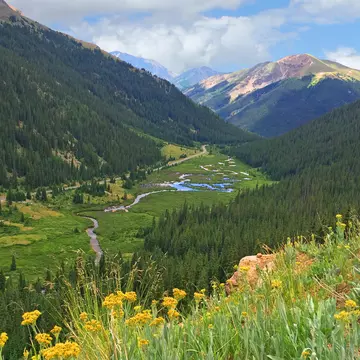 A sweeping, verdant meadow with water running through its valley