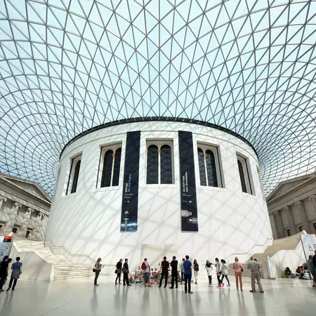 People stand inside the cavernous and modern interior of the British Museum in London. 